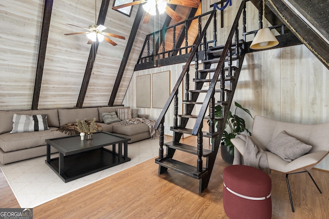 living room featuring lofted ceiling with beams, stairway, a ceiling fan, and wood finished floors