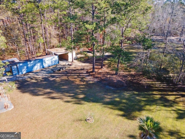 view of yard with an outbuilding and a view of trees