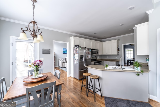 kitchen with kitchen peninsula, stainless steel appliances, pendant lighting, an inviting chandelier, and white cabinets