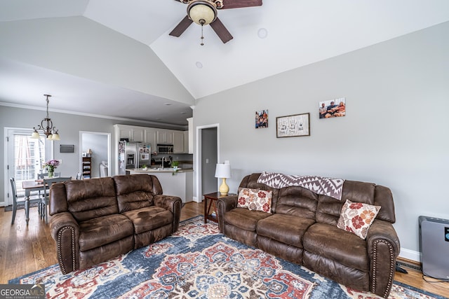 living room featuring ceiling fan with notable chandelier, light hardwood / wood-style floors, and lofted ceiling