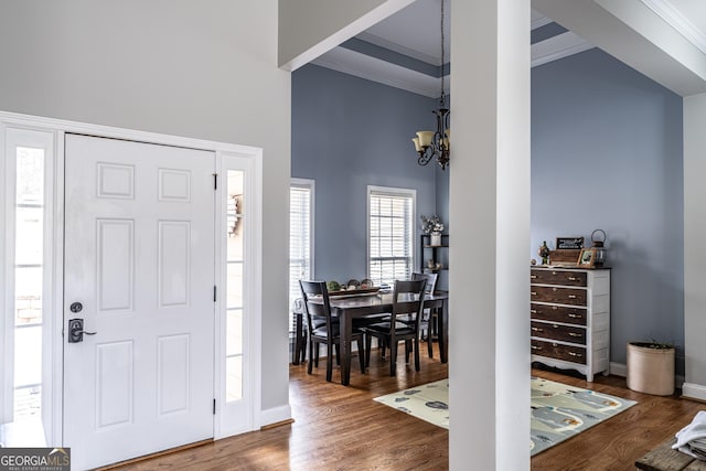 entrance foyer with a notable chandelier, dark hardwood / wood-style flooring, a high ceiling, and ornamental molding