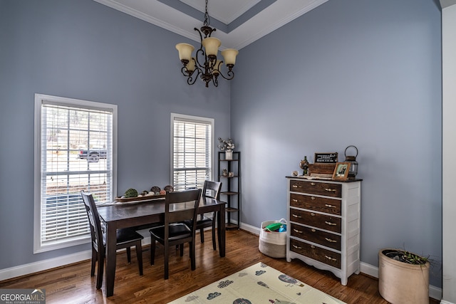 dining area featuring dark hardwood / wood-style floors, ornamental molding, a tray ceiling, and an inviting chandelier