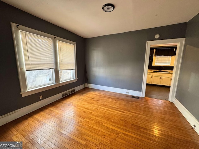 spare room featuring sink and light hardwood / wood-style flooring