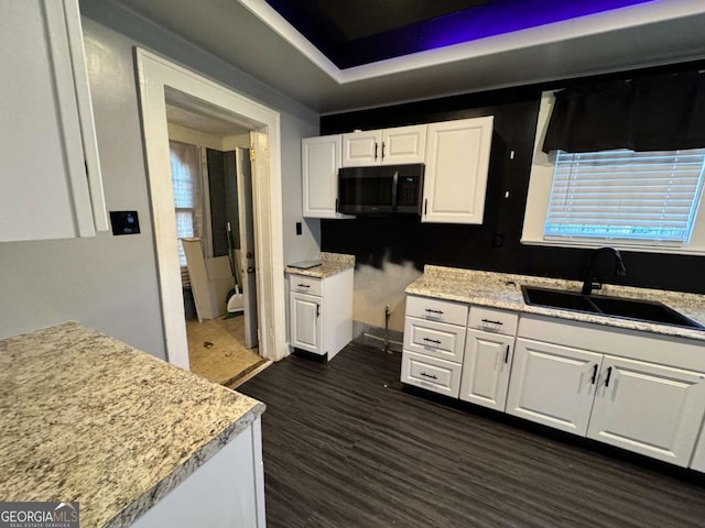 kitchen with white cabinetry, sink, light stone countertops, and dark hardwood / wood-style floors