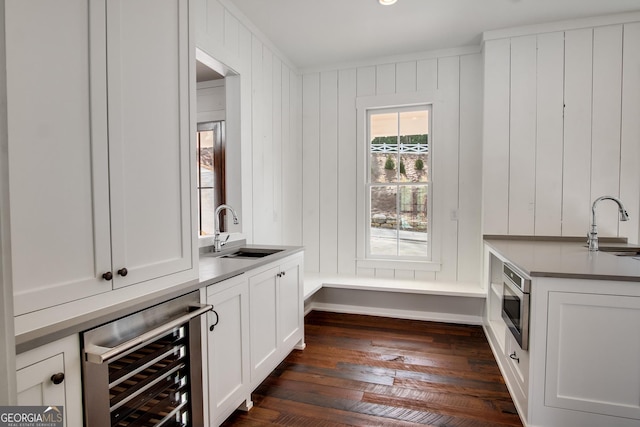 bar with wine cooler, white cabinetry, sink, and dark hardwood / wood-style floors