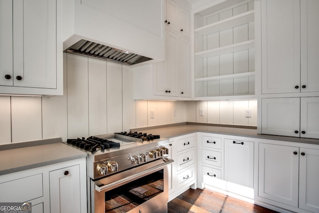 kitchen featuring high end stove, backsplash, white cabinets, and custom exhaust hood