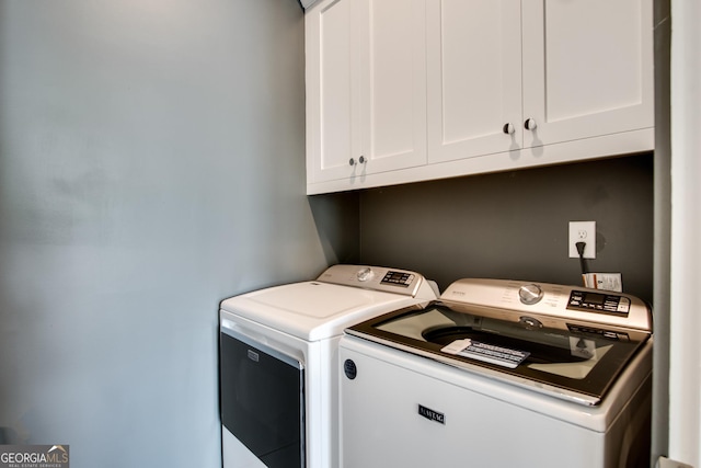 clothes washing area featuring cabinets and washer and clothes dryer