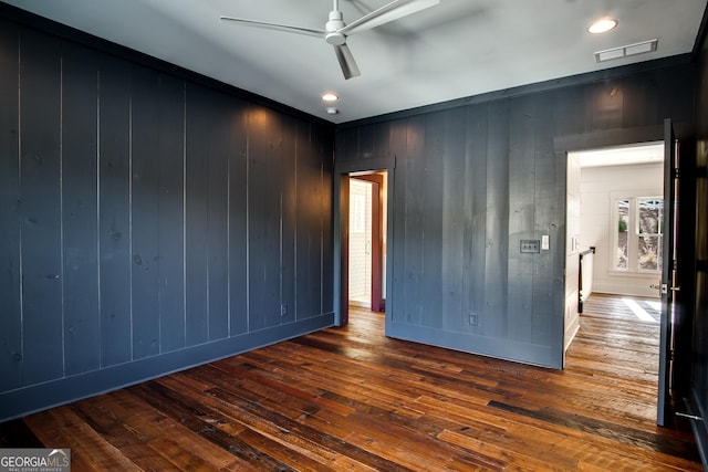 unfurnished room with ceiling fan, dark wood-type flooring, and wood walls