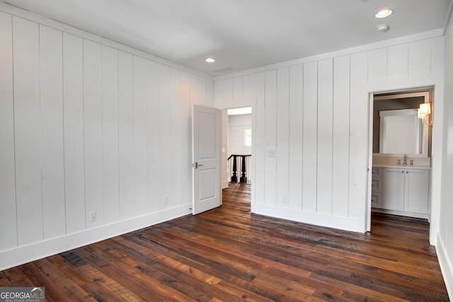 unfurnished bedroom featuring sink, dark wood-type flooring, and connected bathroom