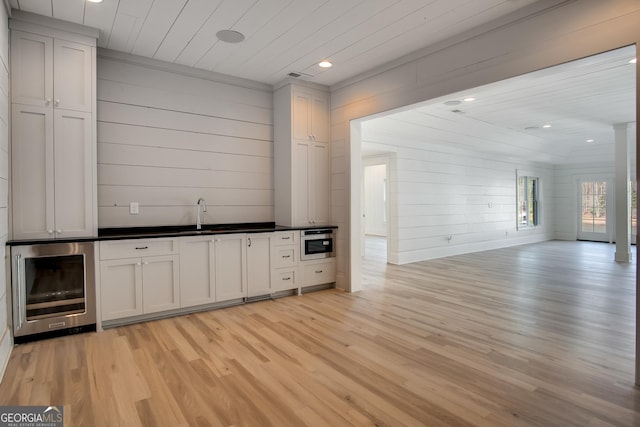 bar featuring wood ceiling, wooden walls, sink, light hardwood / wood-style flooring, and wine cooler