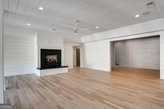 unfurnished living room with wood walls, ceiling fan, wood ceiling, and light wood-type flooring