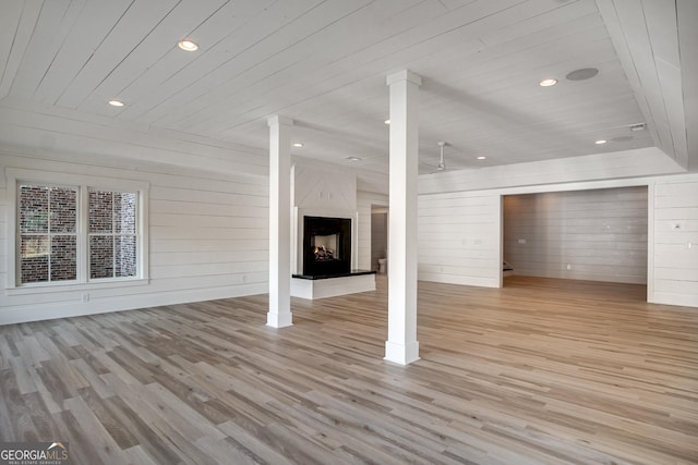 unfurnished living room featuring light hardwood / wood-style floors, wood walls, wooden ceiling, and a fireplace