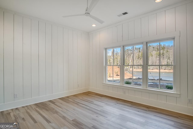 empty room with ceiling fan and light hardwood / wood-style flooring