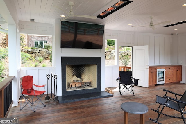 living area featuring wine cooler, ceiling fan, dark wood-type flooring, and wooden ceiling