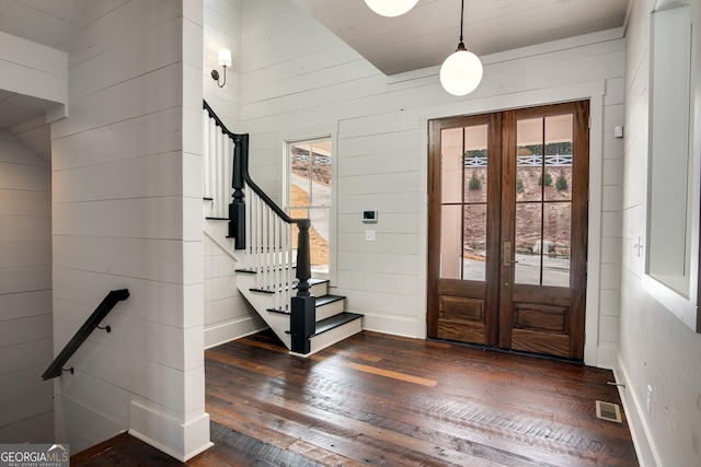 foyer entrance featuring vaulted ceiling, wood walls, french doors, and dark hardwood / wood-style floors