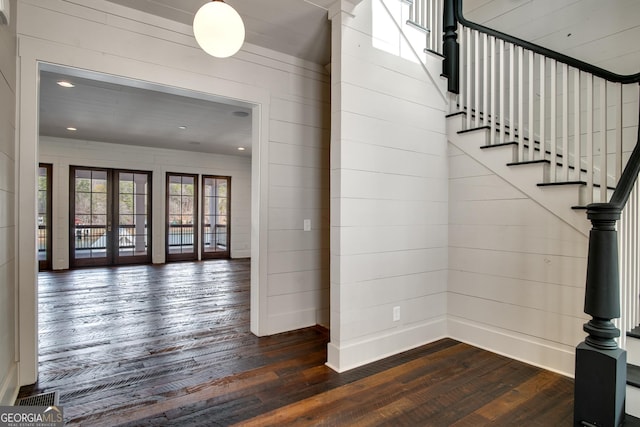 stairs featuring french doors, wooden walls, and hardwood / wood-style floors