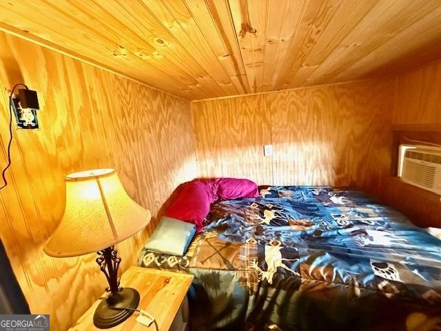 bedroom with a wall unit AC, wood walls, and wooden ceiling