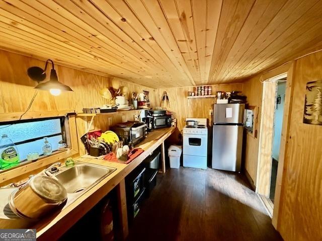 kitchen with wood walls, stainless steel fridge, wood ceiling, and white stove