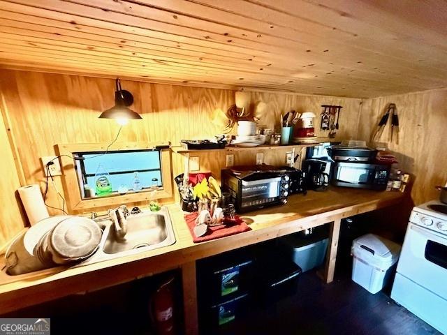 kitchen with pendant lighting, wood walls, wood ceiling, and white stove