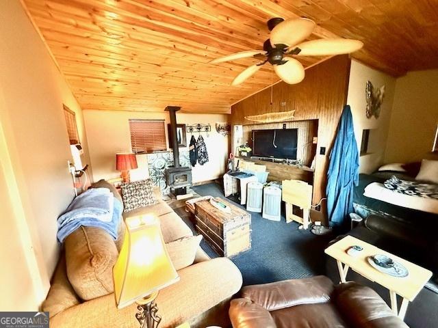 living room with a wood stove, wood ceiling, and lofted ceiling