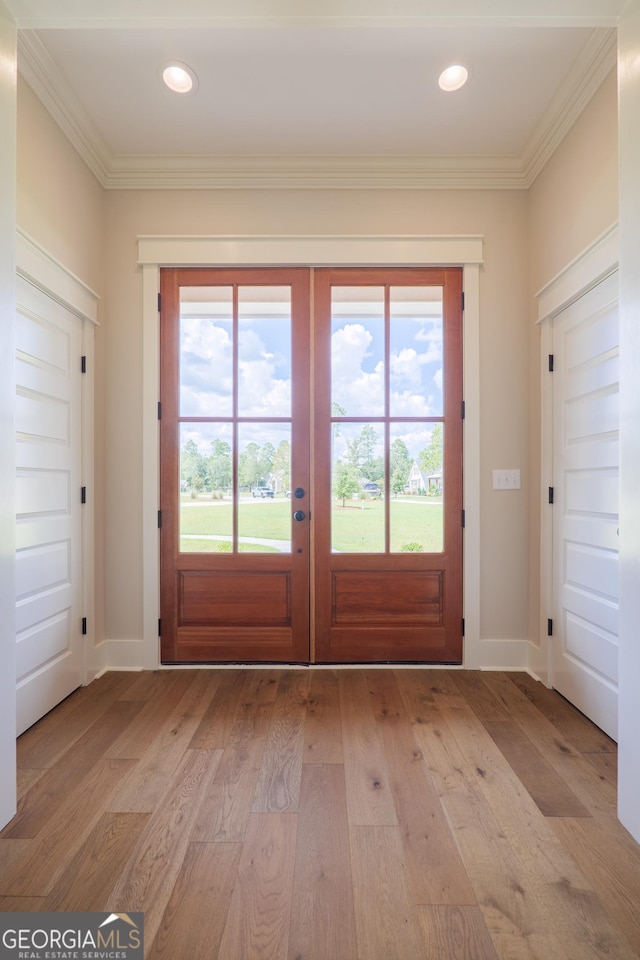 doorway to outside featuring plenty of natural light, light wood-type flooring, and ornamental molding