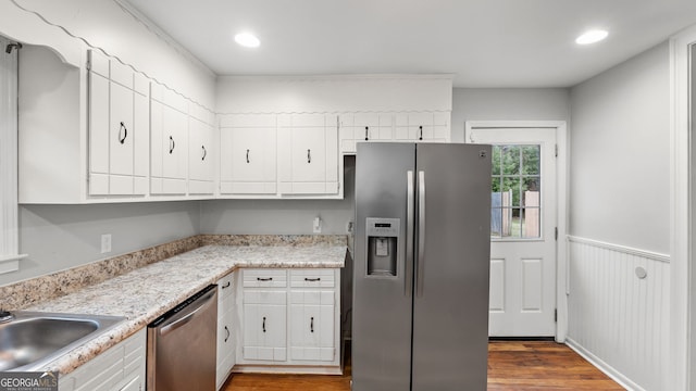 kitchen featuring hardwood / wood-style flooring, appliances with stainless steel finishes, white cabinets, and sink