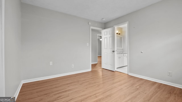 unfurnished bedroom featuring connected bathroom and light hardwood / wood-style floors