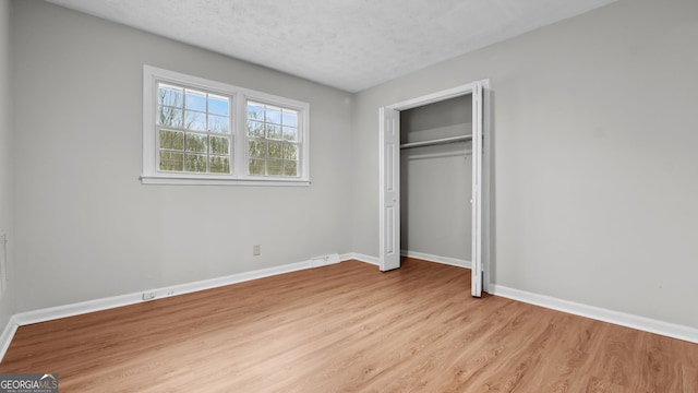 unfurnished bedroom featuring a closet, a textured ceiling, and light hardwood / wood-style flooring