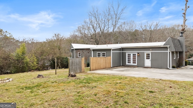 rear view of house featuring a lawn, french doors, and a patio