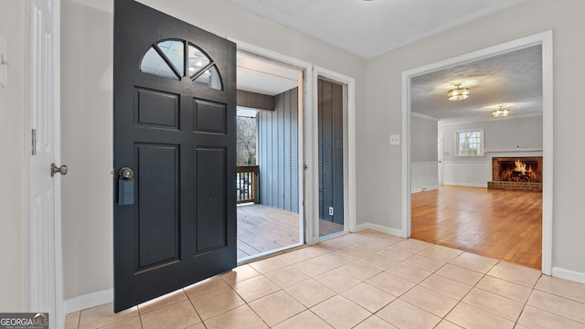 tiled entryway with a brick fireplace and a textured ceiling