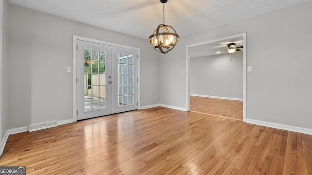 unfurnished room with light wood-type flooring, an inviting chandelier, and french doors