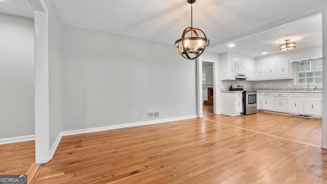 kitchen with pendant lighting, white cabinetry, electric stove, sink, and light wood-type flooring