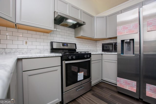 kitchen with light stone countertops, dark hardwood / wood-style flooring, backsplash, stainless steel appliances, and range hood