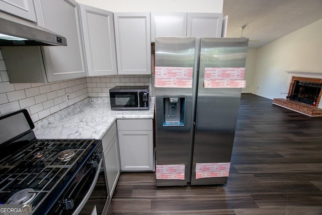 kitchen featuring dark wood-type flooring, a brick fireplace, stainless steel fridge with ice dispenser, backsplash, and black gas stove