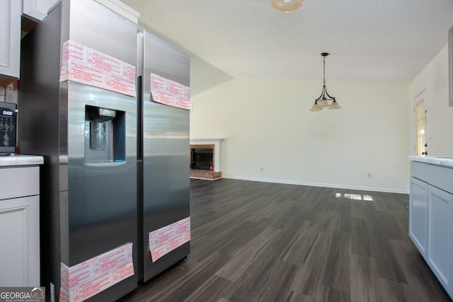 kitchen with pendant lighting, white cabinets, stainless steel refrigerator with ice dispenser, a brick fireplace, and dark hardwood / wood-style flooring