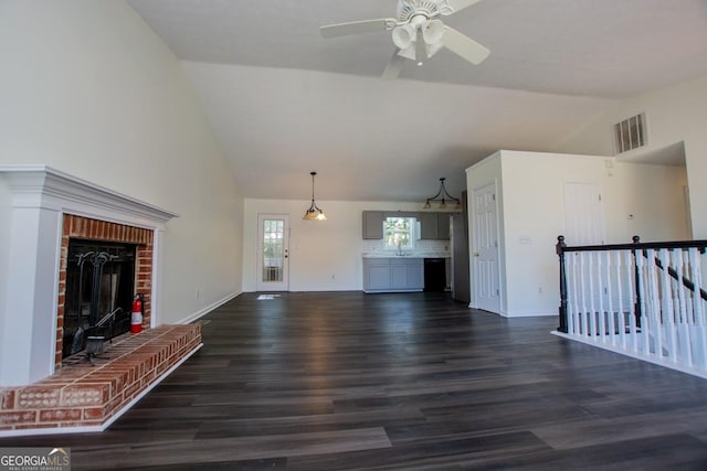 unfurnished living room with dark wood-type flooring, sink, vaulted ceiling, ceiling fan, and a fireplace