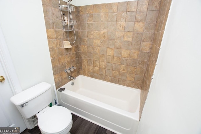 bathroom with hardwood / wood-style floors, toilet, and tiled shower / bath