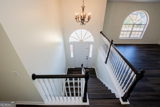 stairs with hardwood / wood-style flooring and an inviting chandelier