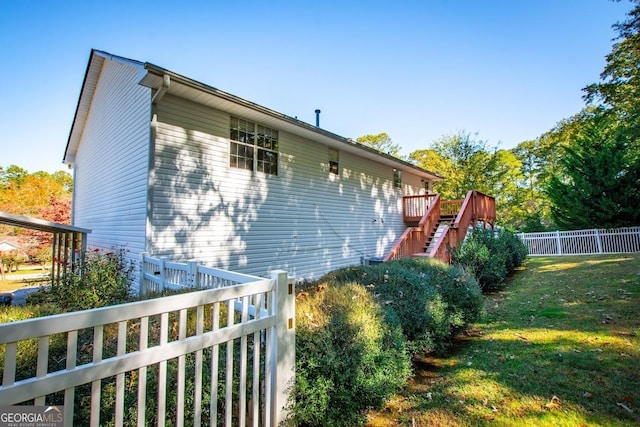 view of side of home featuring a wooden deck and a yard