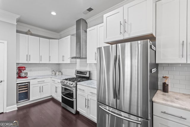 kitchen with white cabinetry, beverage cooler, stainless steel appliances, and wall chimney range hood