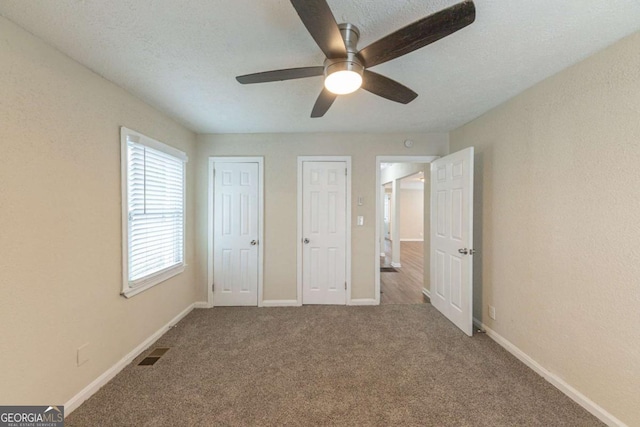 unfurnished bedroom featuring carpet flooring, ceiling fan, and a textured ceiling