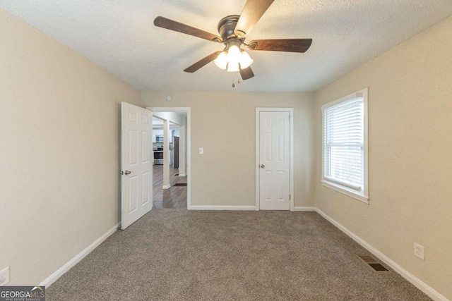 unfurnished bedroom featuring a textured ceiling, carpet floors, and ceiling fan