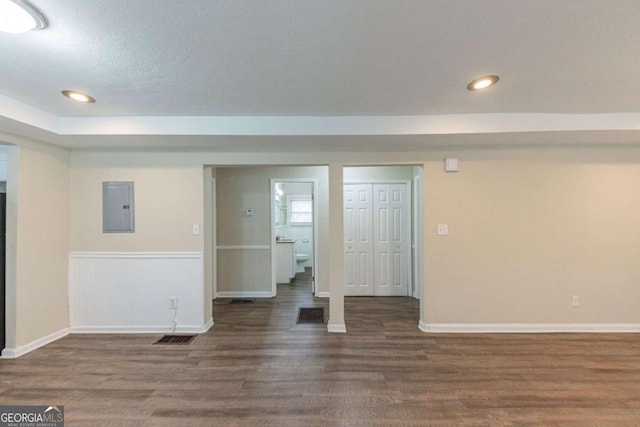 unfurnished room with a textured ceiling, electric panel, and dark hardwood / wood-style floors