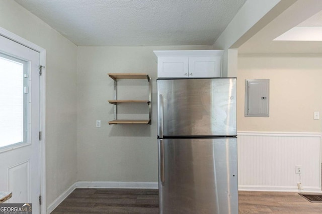 kitchen with stainless steel refrigerator, electric panel, hardwood / wood-style floors, a textured ceiling, and white cabinets