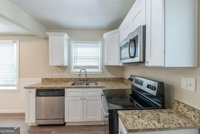 kitchen featuring light stone countertops, appliances with stainless steel finishes, white cabinetry, and sink