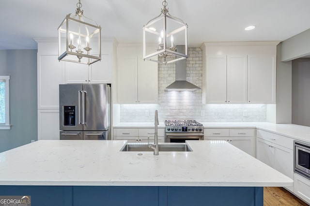 kitchen with an inviting chandelier, wall chimney exhaust hood, a sink, high quality appliances, and decorative backsplash