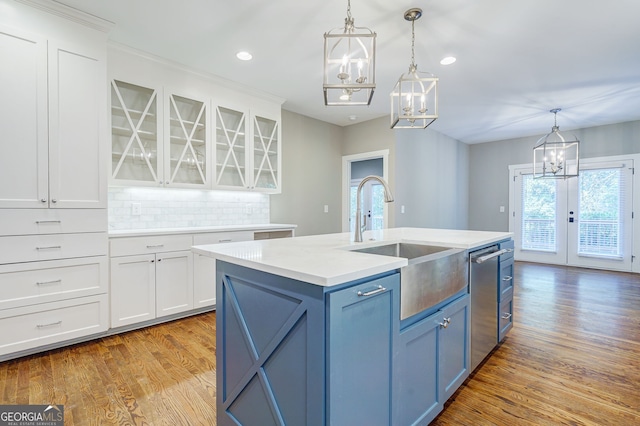 kitchen with a notable chandelier, dishwasher, a sink, white cabinetry, and blue cabinets