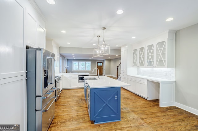 kitchen with sink, stainless steel appliances, tasteful backsplash, a kitchen island with sink, and white cabinets