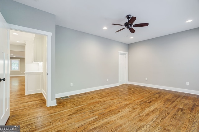 spare room featuring ceiling fan, light wood-style floors, and baseboards