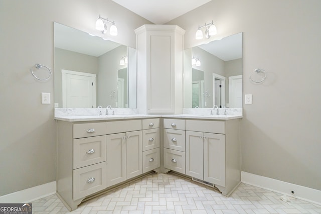 bathroom with double vanity, baseboards, and a sink